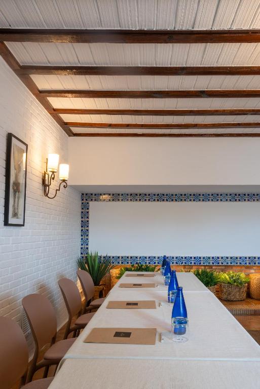 a long table in a room with white tables and chairs at Parador de Mazagón in Mazagón