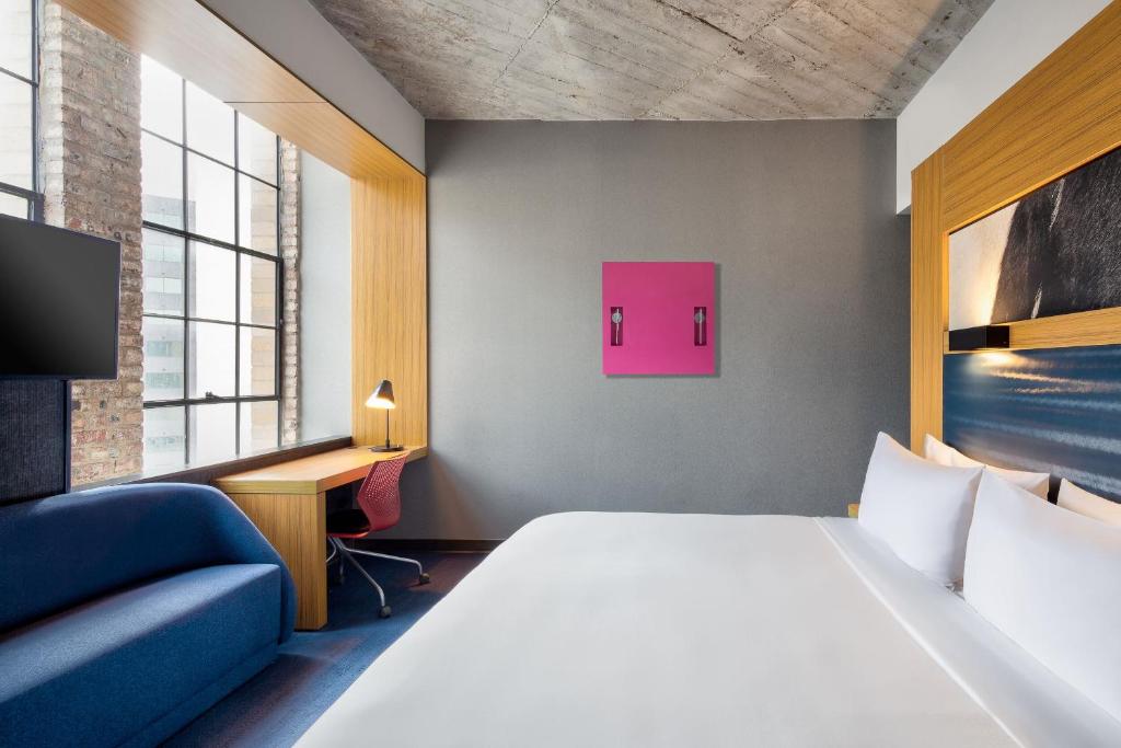 a hotel room with a bed and a couch and a tv at Aloft Dallas Downtown in Dallas