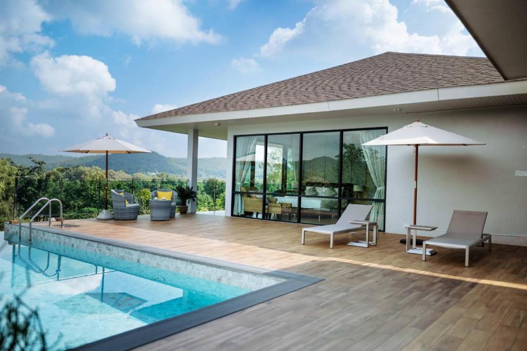 a house with a swimming pool and a patio with chairs and umbrellas at Empreo Residence Pool Villa (เอมพรีโอ พูล วิลลา) in Ban Thung Satong