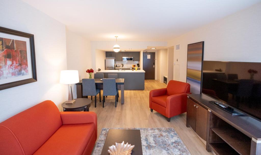 a living room with a couch and a television and a dining room at Les Suites Hotel in Ottawa