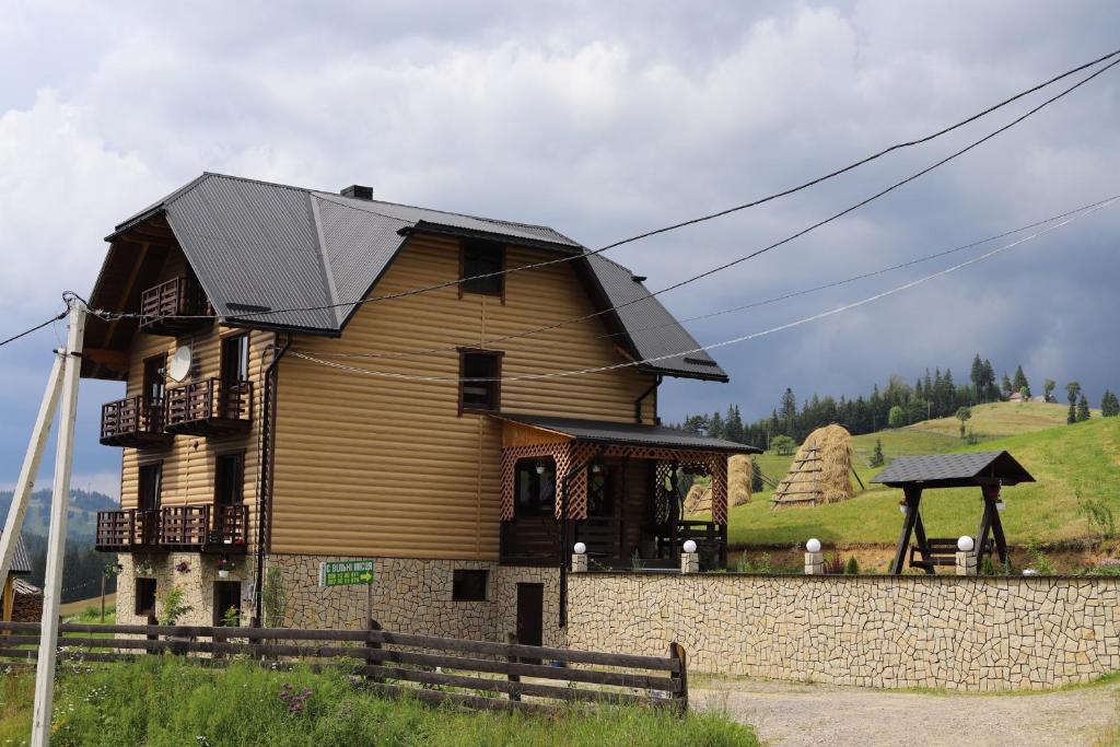 a wooden house with a black roof on a hill at Приватна садиба SHAFRAN in Yablunytsya