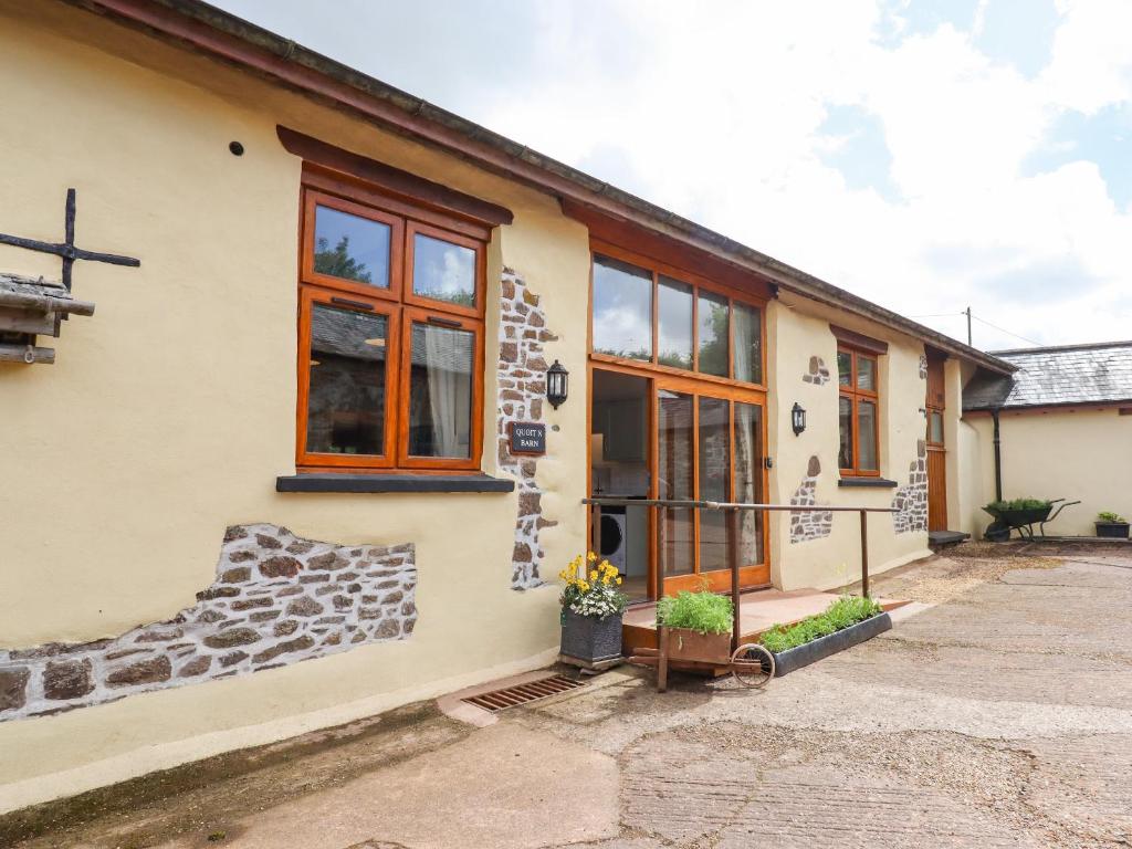una casa con fachada de piedra y ventanas en Quoit X Barn, en Tiverton