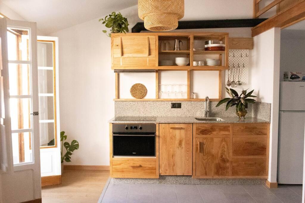 La cuisine est équipée de placards en bois et d'un four avec plaques de cuisson. dans l'établissement Ferreiros - Wood Design apartments, à Pontedeume