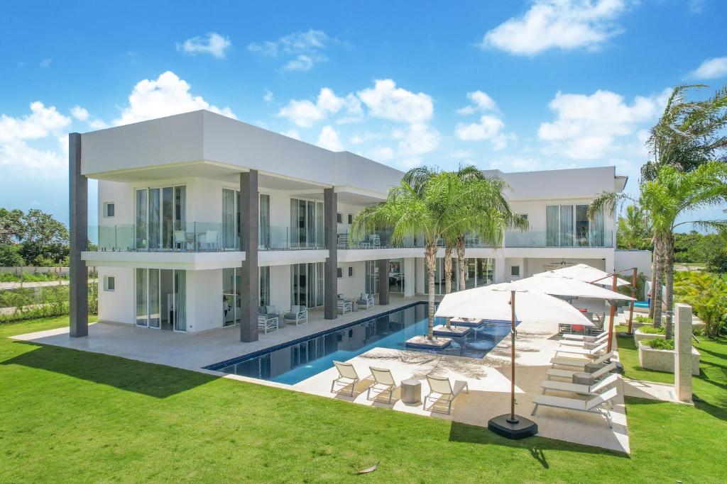 an exterior view of a house with a swimming pool at Exquisite Contemporary 8BR Pool Villa with Chef, Butler, Maid, and Eden Roc Beach Club Access in Punta Cana