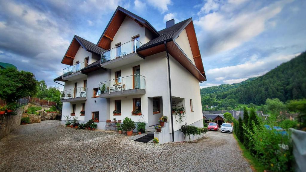 a white building with a balcony on a hill at Willa Kania in Szczawnica