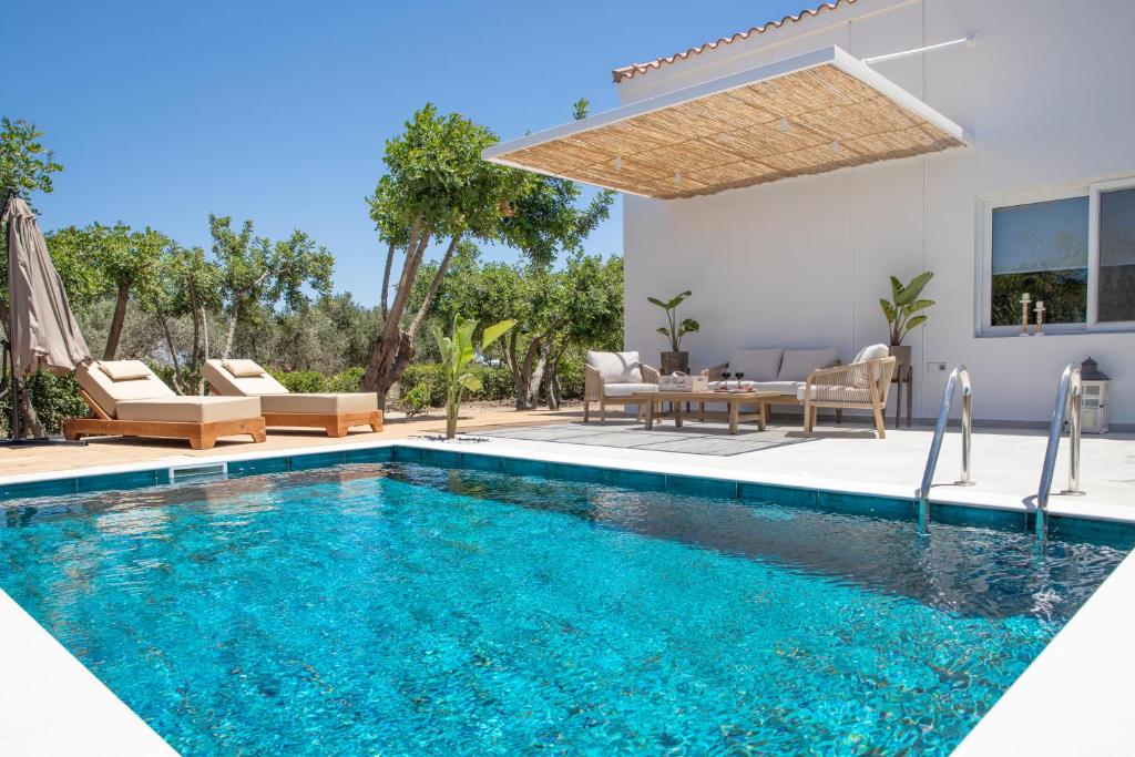 uma piscina numa villa com mesa e cadeiras em EPTA Houses em Marmari