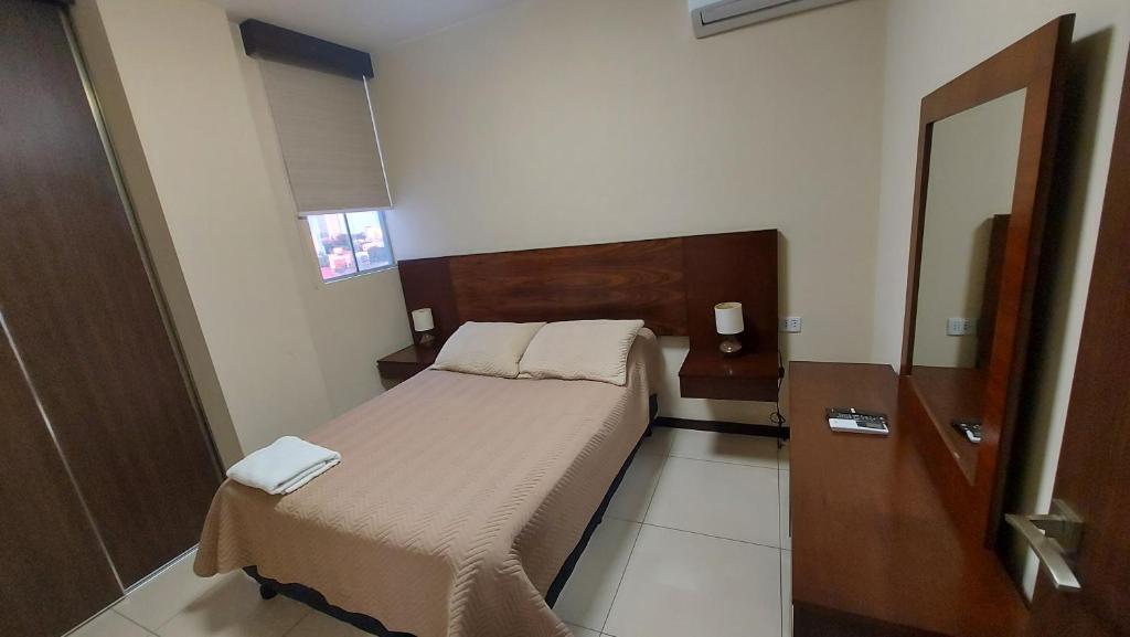 a small bedroom with a bed and a mirror at Apartamento amplio y moderno en el centro de Santa Cruz, con PARQUEO e Internet, cerca de EQUIPETROL in Santa Cruz de la Sierra