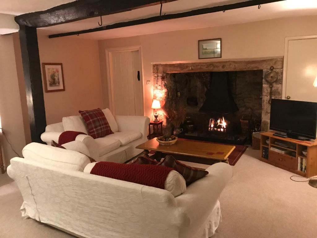 a living room with white furniture and a fireplace at The Old House Cottages in Nether Stowey