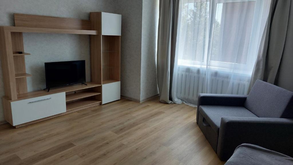 een woonkamer met een tv, een bank en een raam bij Лучшее жилье для отпуска в г. Sillamäe in Sillamäe