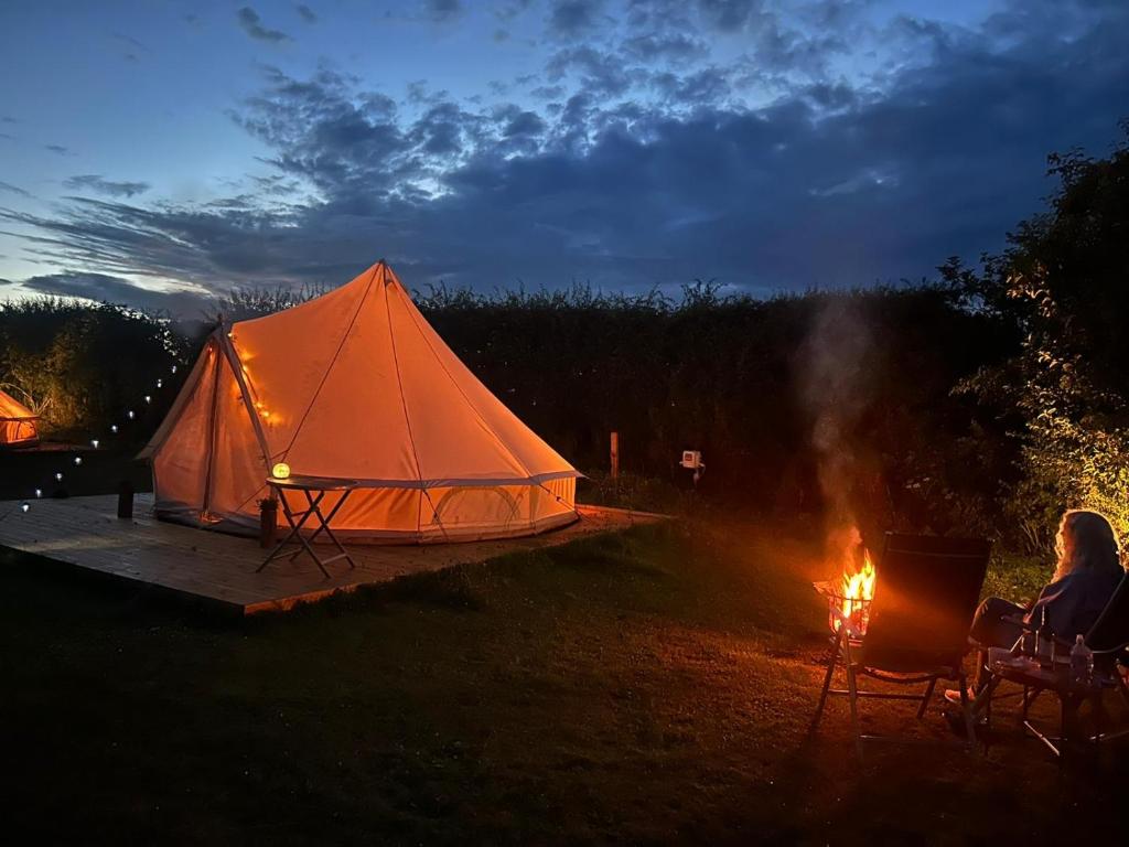 a woman sitting in chairs next to a tent at Roe Deer Meadow at Carr House Farm in Scarborough