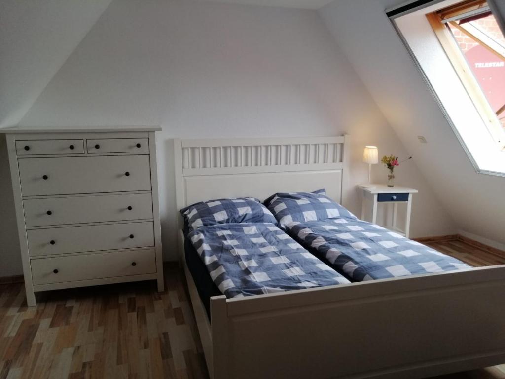 ein Schlafzimmer mit einem Bett, einer Kommode und einem Fenster in der Unterkunft Wellenbude in Otterndorf