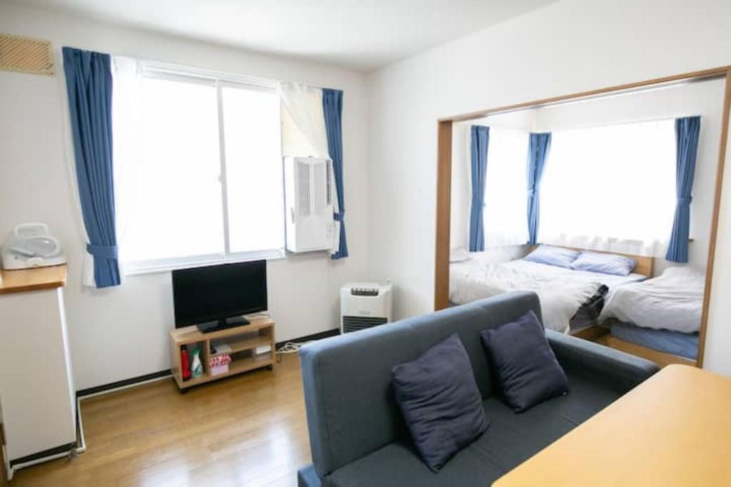 uma sala de estar com um sofá e um quarto em Dream Misono - Vacation STAY 14776 em Sapporo