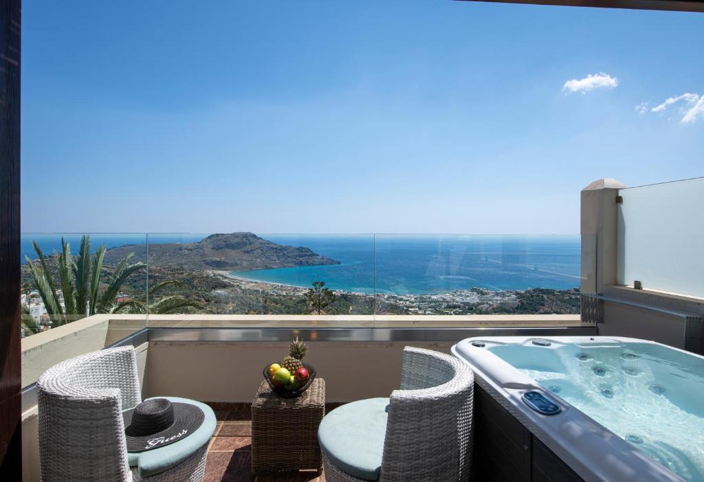 a balcony with a tub and chairs and a view at Stefanos Village Hotel in Plakias