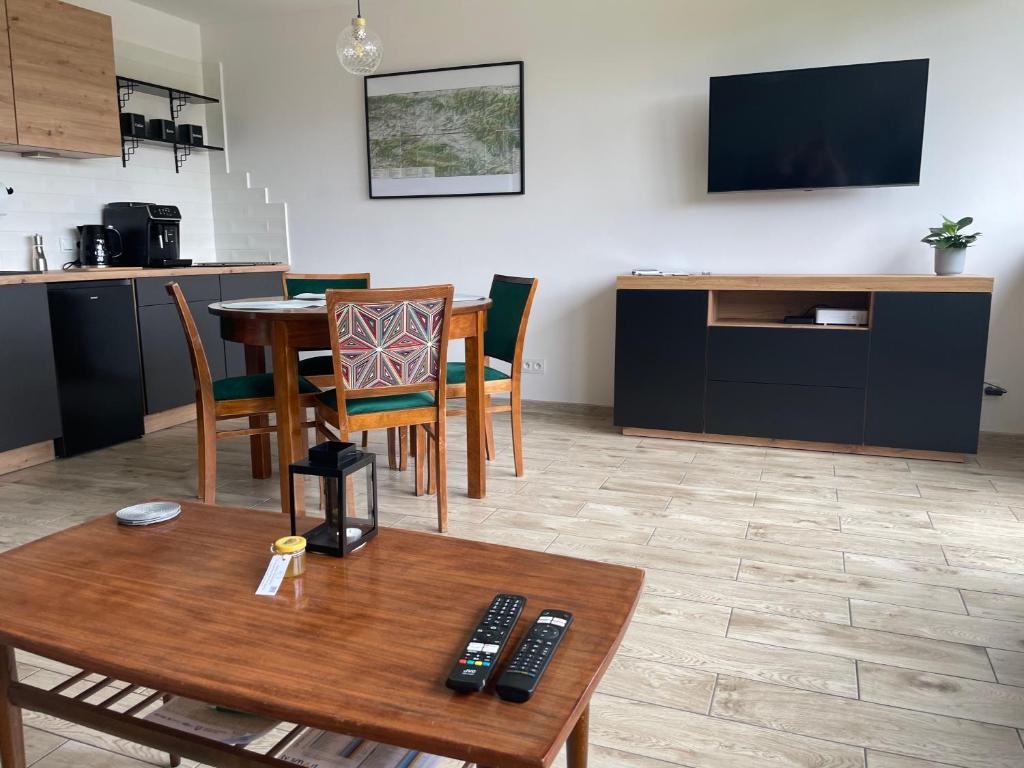 ein Wohnzimmer mit einem Tisch und Stühlen sowie einem TV in der Unterkunft Apartamenty Stronie Śląskie in Stronie Śląskie