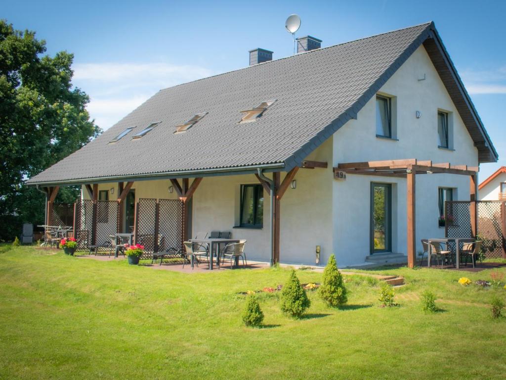 ein weißes Haus mit grauem Dach auf einem Hof in der Unterkunft Apartamenty - Dom Smołdziński Las in Smołdziński Las