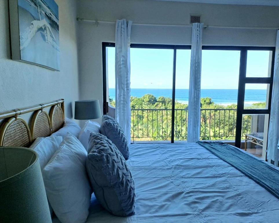 a bedroom with a bed with a view of the ocean at 8 Eden Palms, Palm Beach in Port Edward