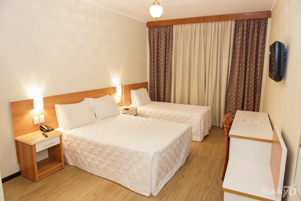 Habitación de hotel con 2 camas y TV en Hotel San Silvestre, en Tubarão