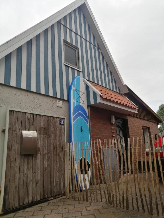 ein Gebäude mit einem Surfbrett an der Seite in der Unterkunft Wellenbude in Otterndorf