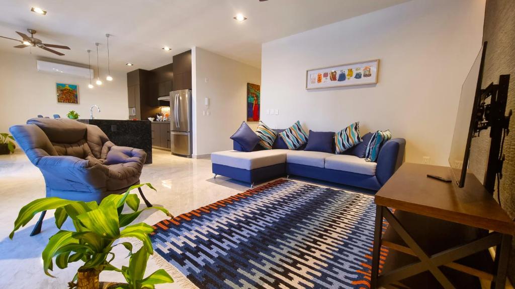a living room with a blue couch and a rug at Palacio Huatulco - 2I in Santa Maria Huatulco