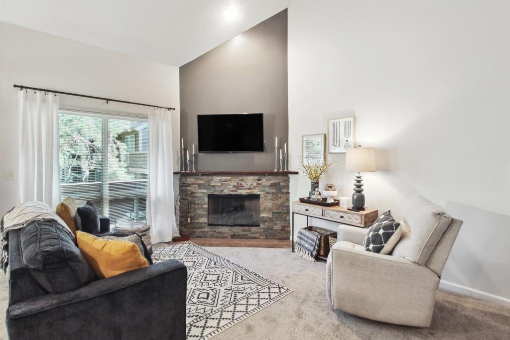 a living room with two chairs and a fireplace at Overland Park Condo, Close to Lakes and Parks! in Overland Park