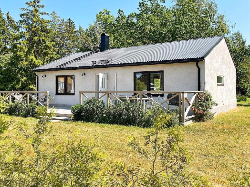 a white house with a black roof on a field at 4 person holiday home in KLINTEHAMN-By Traum in Klintehamn