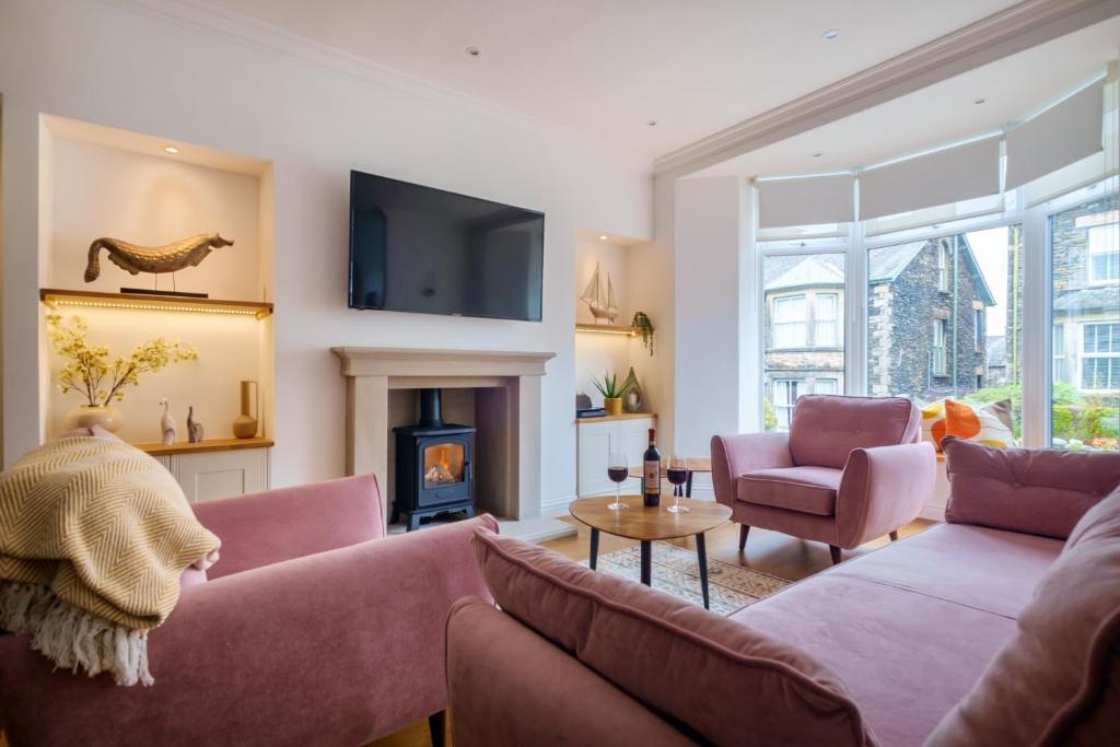 sala de estar con 2 sofás rosados y chimenea en Canon Craig, Luxurious Lakeland stone Cottage en Bowness-on-Windermere