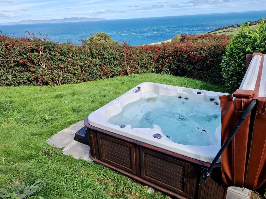 una vasca da bagno situata sull'erba vicino all'oceano di Torr Lodge- luxury log cabin with private hot tub! a Ballycastle
