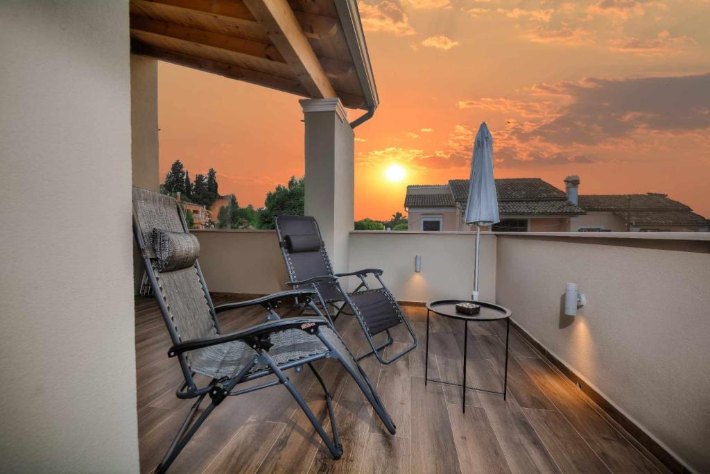 two chairs and a table on a balcony with a sunset at Stratos House 2BR Parking near CorfuTown in Alepou