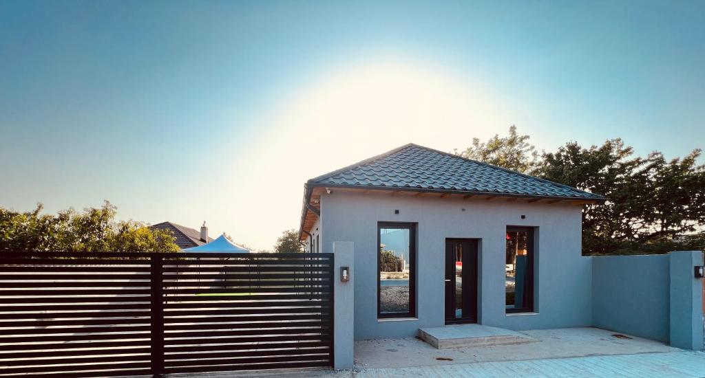 une petite maison blanche avec une clôture noire dans l'établissement ALEX’S BEACH HOUSE, à Corbu