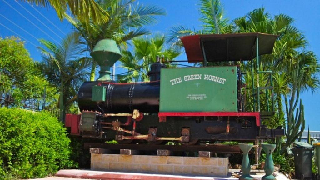 a train on display in front of palm trees at A Railway Lodge in Taree