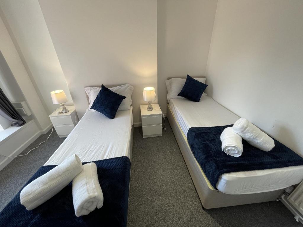 two beds in a room with blue and white pillows at Courtyard Stay in Norwich