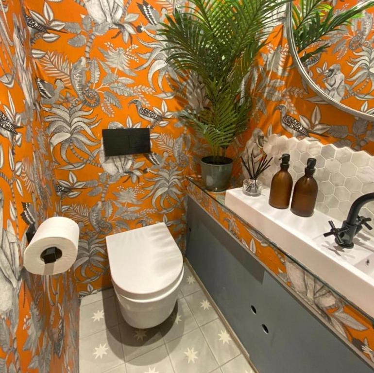 an orange bathroom with a toilet and a sink at Classy House Boat on Penton Hook Marina - walking distance Thorpe Park in Thorpe