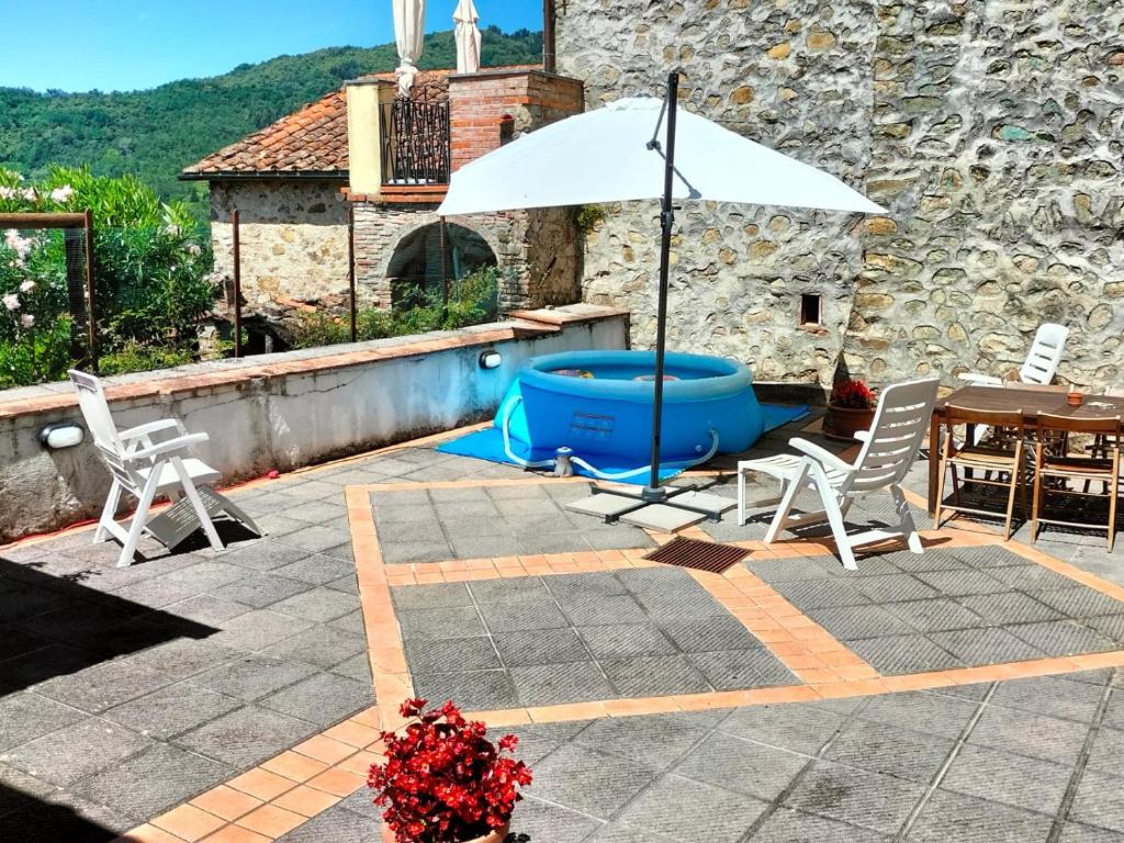 un patio con sombrilla, mesa y sillas en casa Dany, en Bagni di Lucca