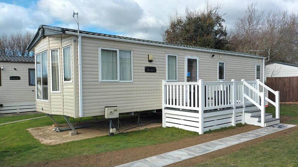a mobile home with a porch and a white railing at The Nook, White Horse, Selsey in Selsey