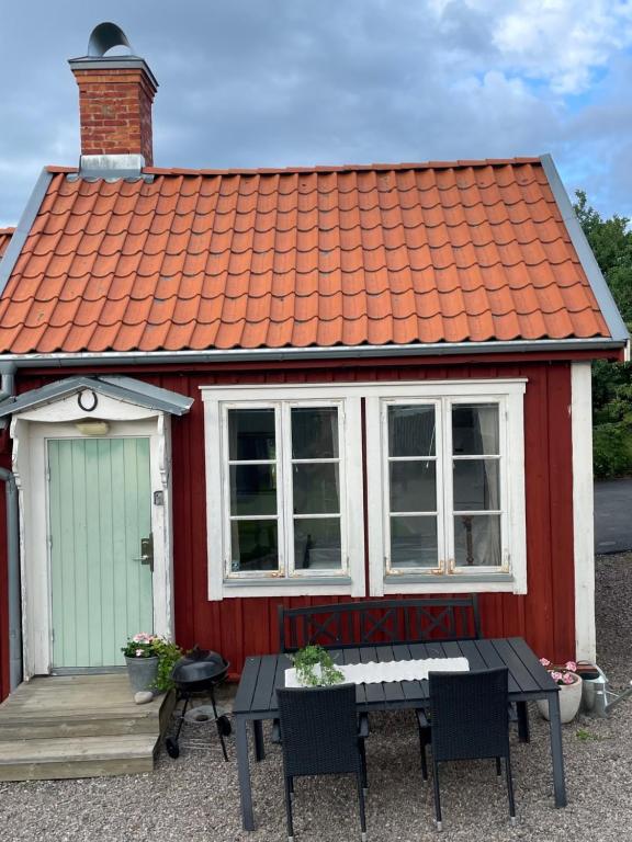 een rood-wit huis met een tafel en stoelen bij Gårdshus - best location in the center of Gränna in Gränna