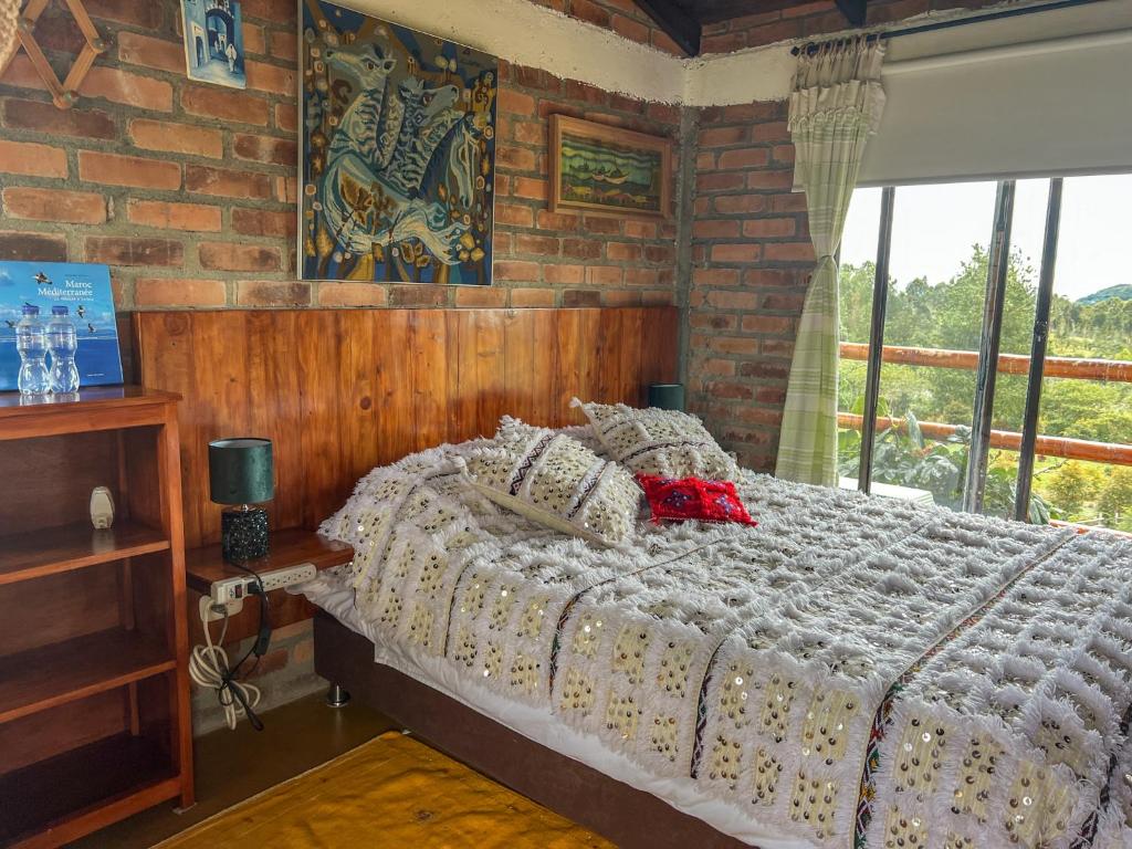 a bedroom with a bed and a brick wall at Campground Hostal La Bonanza Chez Kika in Piendamó