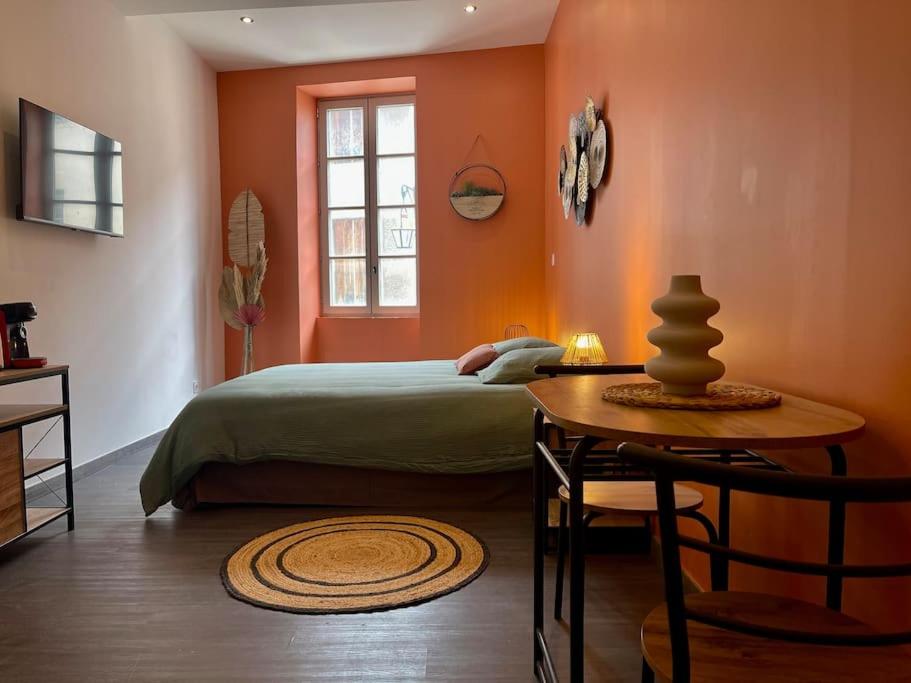 a bedroom with orange walls and a bed and a table at Rooftop N°38 - Rooms et Studios - Vue Cité Médiévale in Carcassonne