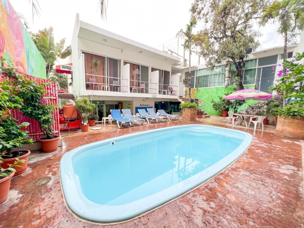 a large pool in a yard with chairs and a building at ITH Amazing Hostel Sayulita in Sayulita