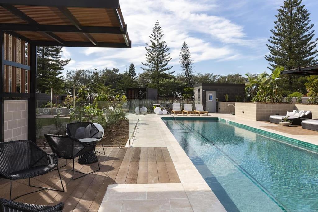 a swimming pool with two chairs and a table at Burleigh Beach Escape with Stunning Sunset Views in Gold Coast