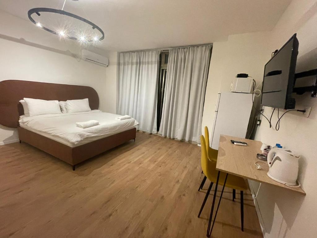 een kleine kamer met een bed, een bureau en een computer bij דירות רוטשילד in Petach Tikwa