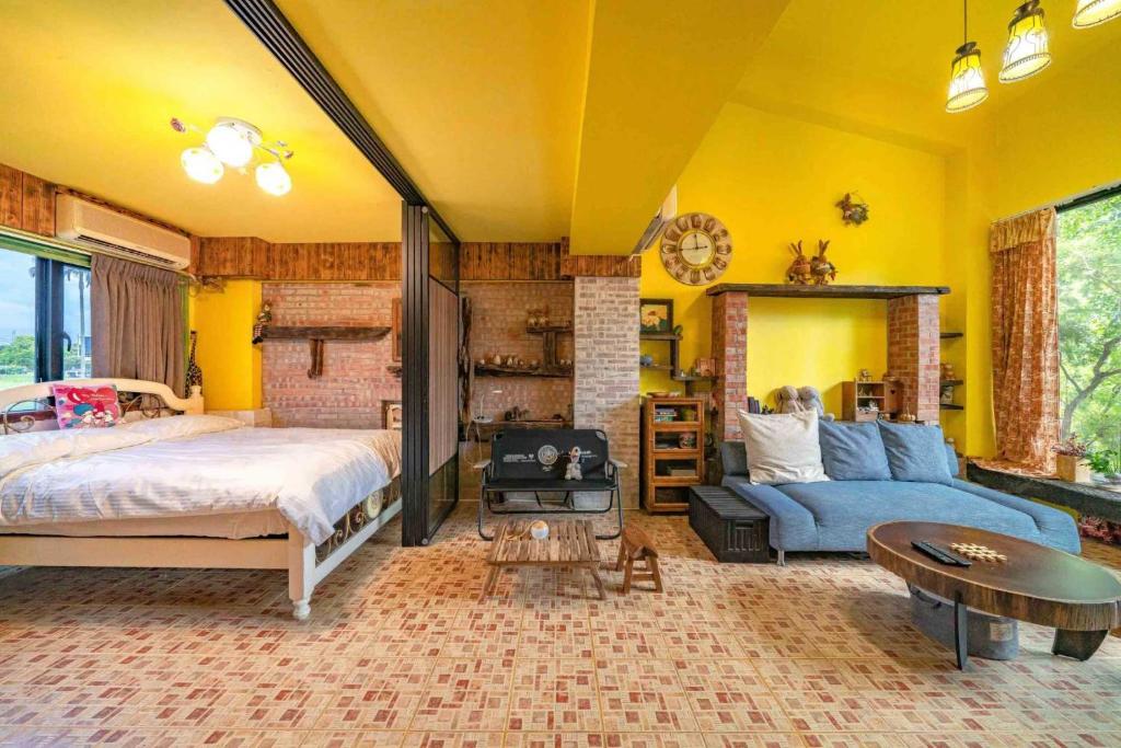 1 dormitorio con paredes amarillas, 1 cama y 1 sofá en 兔窩很Chill en Yilan City