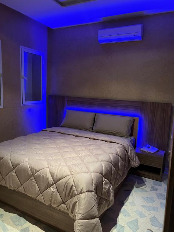 een slaapkamer met een bed met een blauw licht bij Magnifique villa avec un grand jardin et une cascade in Agadir