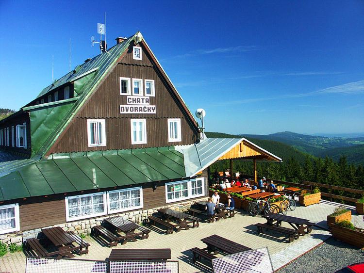 un grande edificio in legno con persone sedute fuori da esso di Horska Bouda Dvoracky a Rokytnice nad Jizerou