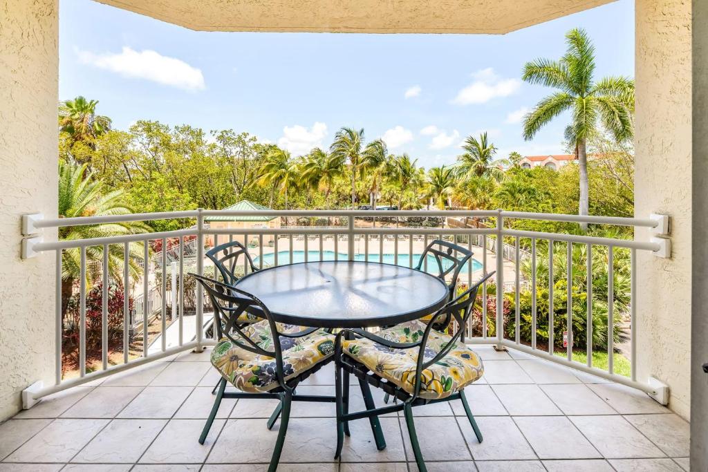 a table and chairs on a balcony with palm trees at The St Martin by Brightwild-Hot Tub & Pool in Key West