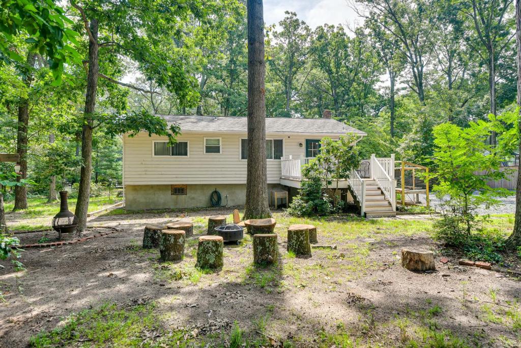 a house with a yard with trees and logs at Pasadena Hideaway with Game Room and Fire Pit! in Glen Burnie