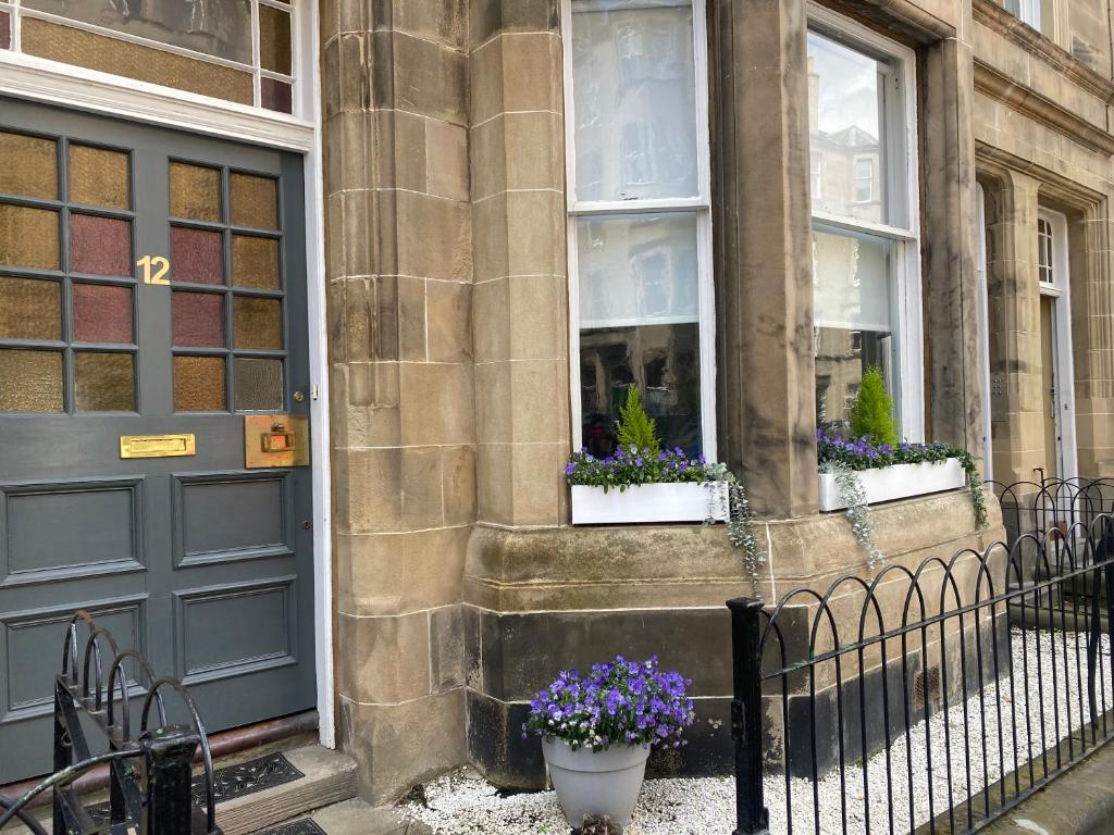 a building with a door and two windows with flowers at Lovely main door 2 bed apartment in Edinburgh