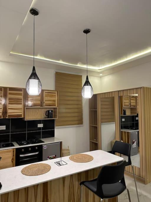 kuchnia z 2 lampkami oraz stołem i krzesłami w obiekcie MCM _Haven w mieście Dar es Salaam
