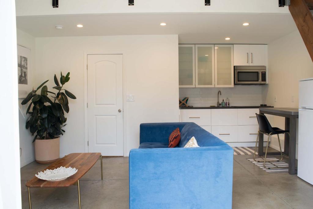 a living room with a blue couch and a kitchen at English Cottage Guest House walk to the Grove and lots of attractions in Los Angeles