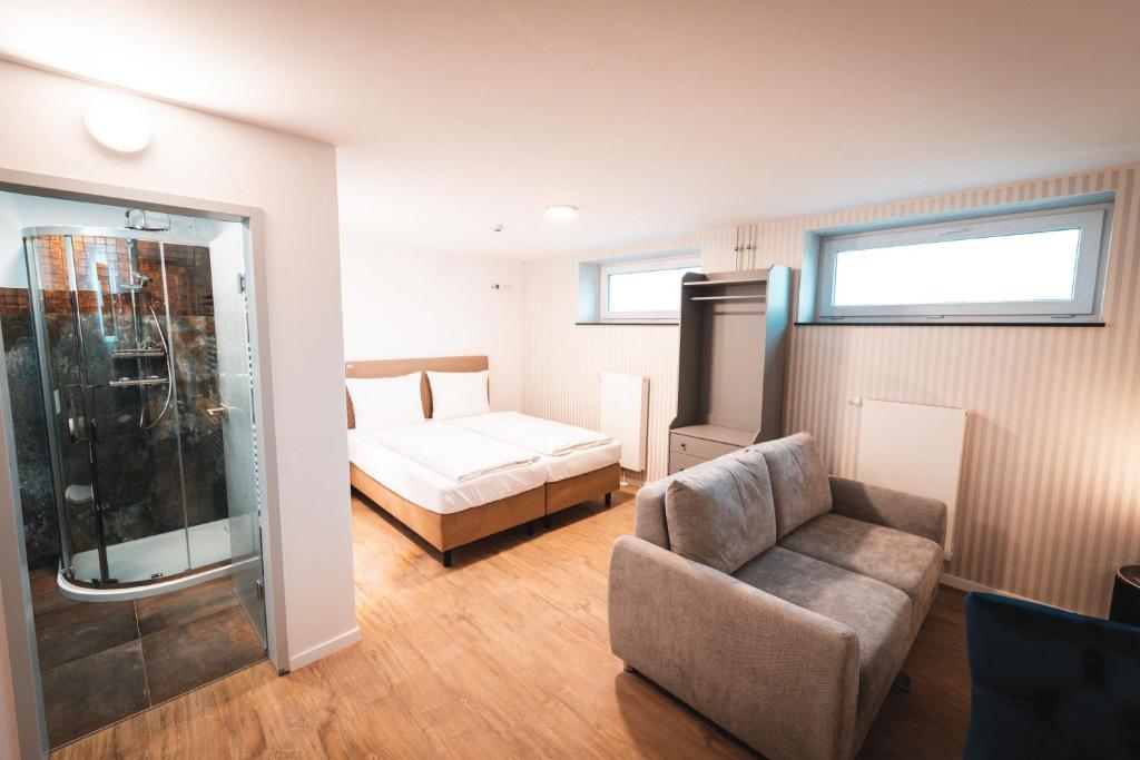 een slaapkamer met een bed, een bank en een stoel bij Hotel Elbe-Herz-Appartement in Wittenberge