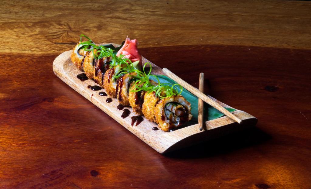 een bord sushi op een houten tafel met eetstokjes bij Hotel Playa Cambutal in Cambutal